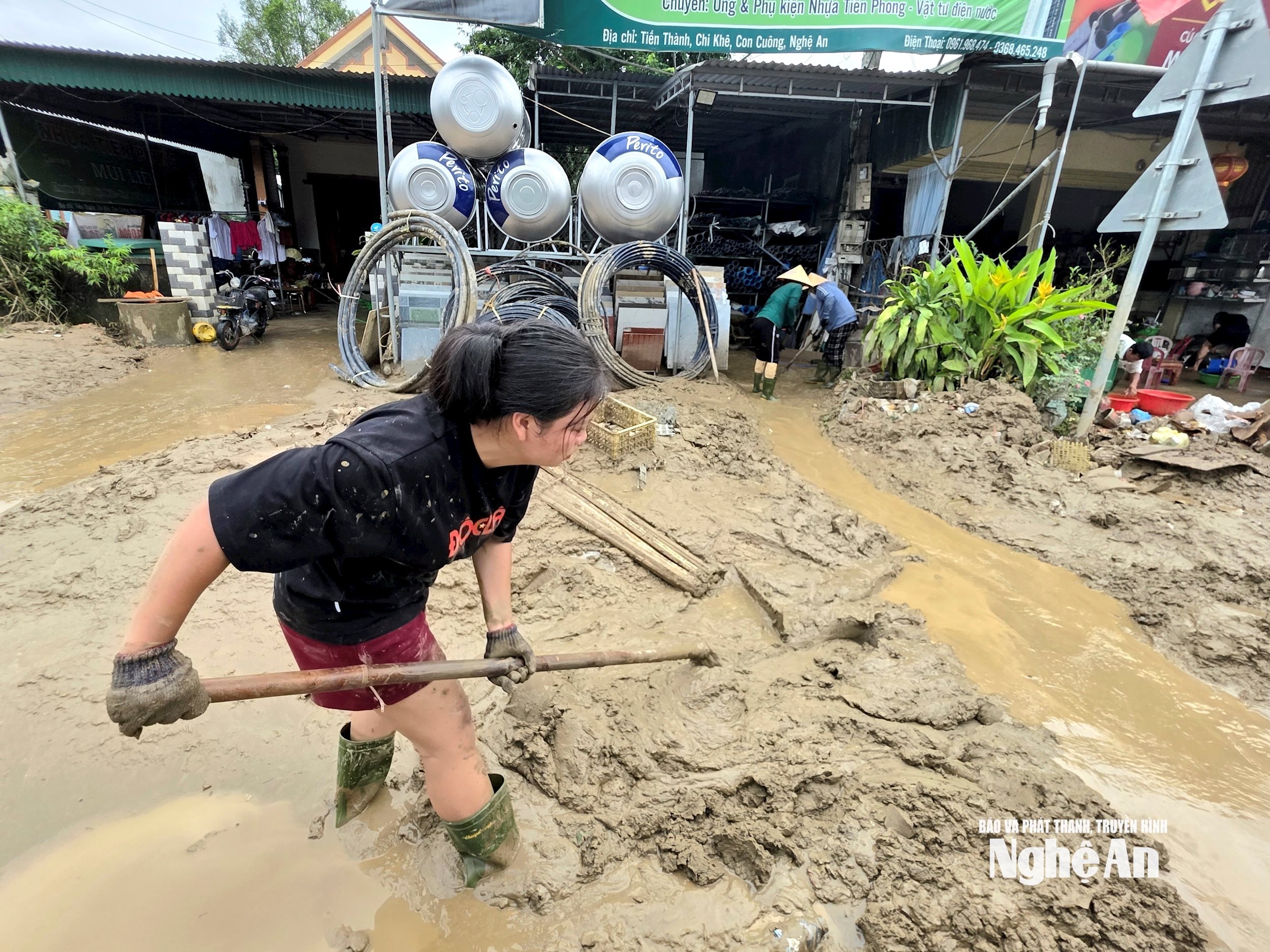 Chị Trần Thị Thảo chung tay cùng bà con thôn Tiến Thành giải phóng bùn, đất trên Quốc lộ 7. Ảnh: Hoài Thu